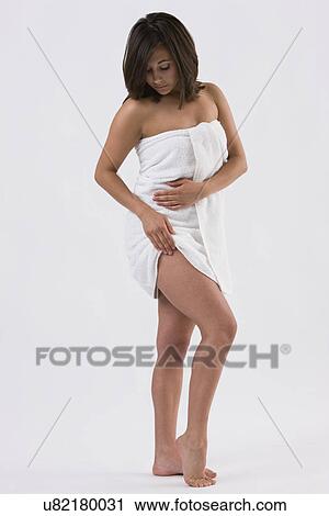 Stock Image - Woman wrapped in towel rubbing thigh. Fotosearch