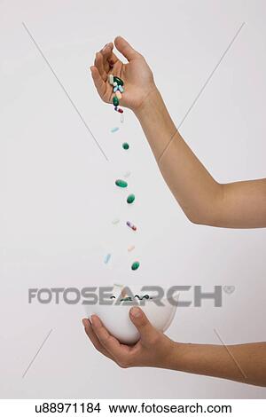 Picture - Woman's hands pouring pills into bowl, close-up. Fotosearch