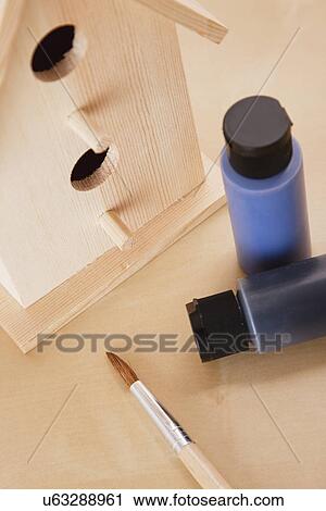 Stock Image - Wooden birdhouse with paints and paintbrush. Fotosearch