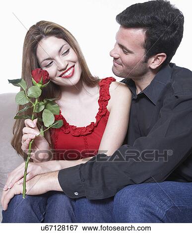 Stock Photo - Young couple embracing on Valentine's day, woman holding rose. Fotosearch