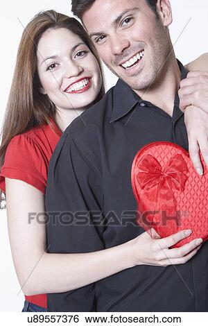 Young couple embracing on Valentine's day, woman holding gift View Large Photo Image Stock Photograph - Young couple embracing on Valentine's day, woman holding gift. Fotosearch