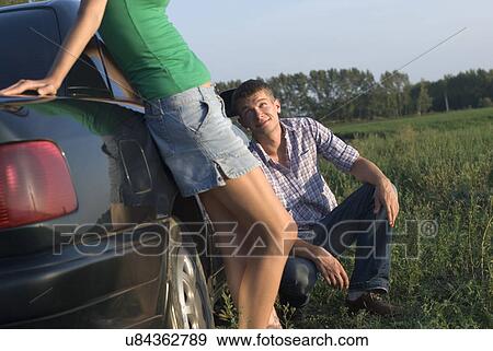 Stock Photo - Young couple leaning to car. Fotosearch