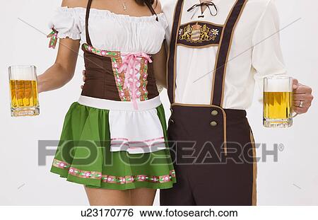 Young couple wearing Oktoberfest costume holding beer stein, studio shot View Large Photo Image Stock Photograph - Young couple wearing Oktoberfest costume holding beer stein, studio shot. Fotosearch