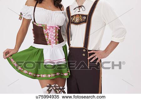 Stock Photography - Young couple wearing Oktoberfest costume holding beer stein, studio shot. Fotosearch