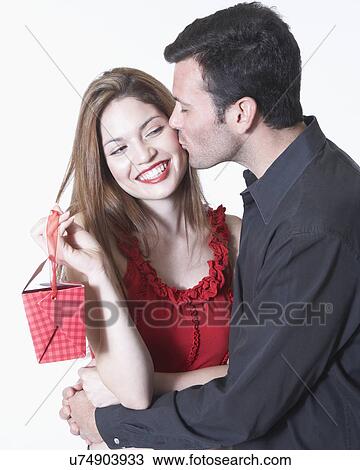 Young man kissing woman on cheek on Valentine's day, woman holding gift View Large Photo Image Stock Image - Young man kissing woman on cheek on Valentine's day, woman holding gift. Fotosearch