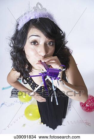 Picture - Young woman blowing party horn, portrait. Fotosearch
