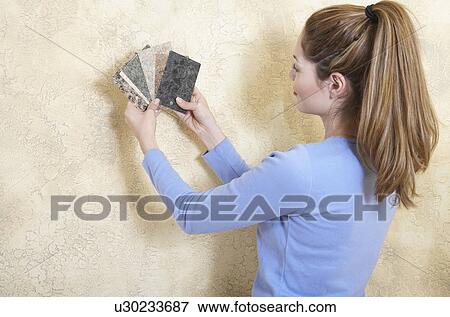 Young woman holding color swatches against wall View Large Photo Image Stock Photo - Young woman holding color swatches against wall. Fotosearch