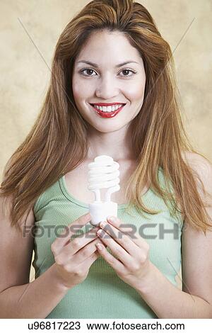 Young woman holding energy saving lightbulb View Large Photo Image Stock Image - Young woman holding energy saving lightbulb. Fotosearch