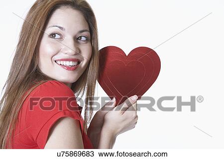 Stock Image - Young woman holding heart shape Valentine card. Fotosearch