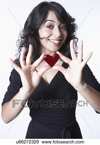 Stock Photo - Young woman holding love heart, portrait. Fotosearch