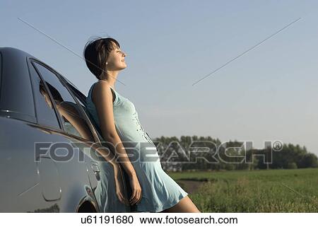 Young woman leaning to car and enjoying sunlight View Large Photo Image Stock Image - Young woman leaning to car and enjoying sunlight. Fotosearch