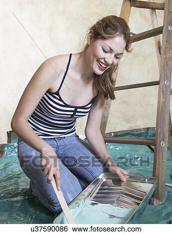 Stock Photograph - Young woman mixing paint in tray. Fotosearch