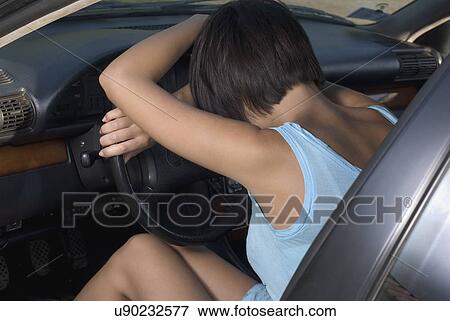 Young woman sitting in car and leaning on steering wheel View Large Photo Image Stock Photo - Young woman sitting in car and leaning on steering wheel. Fotosearch