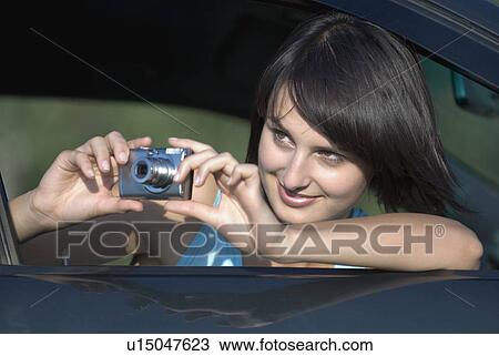 Young woman taking photograph from car window View Large Photo Image Stock Image - Young woman taking photograph from car window. Fotosearch