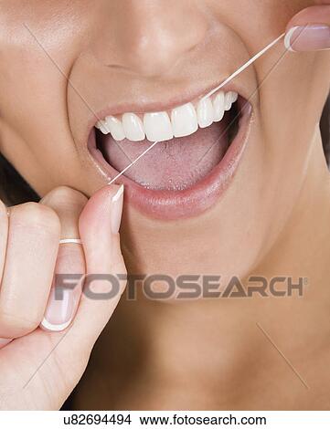 Picture - Young woman using dental floss. Fotosearch