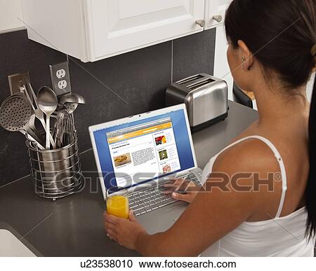 Young woman using laptop in kitchen View Large Photo Image Stock Image - Young woman using laptop in kitchen. Fotosearch