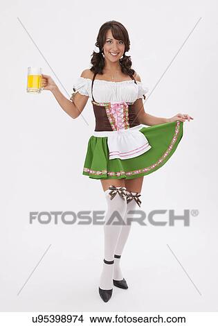 Picture - Young woman wearing Oktoberfest costume holding beer stein, studio shot. Fotosearch