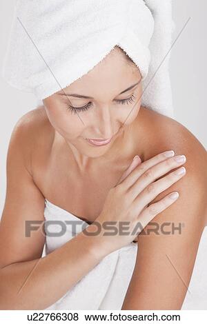 Young woman wrapped in towels touching arm View Large Photo Image Stock Photo - Young woman wrapped in towels touching arm. Fotosearch