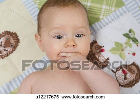 Stock Photography - 7 month old baby girl in crib with fingers in her mouth. Fotosearch
