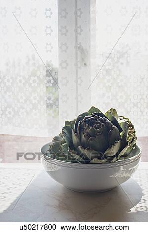 Artichoke in a bowl on sunlit windowsill View Large Photo Image Stock Image - Artichoke in a bowl on sunlit windowsill. Fotosearch