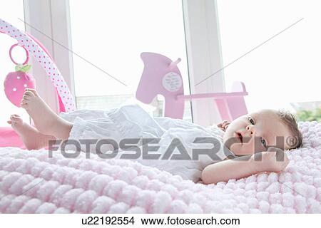 Picture - Baby girl lying in bed. Fotosearch