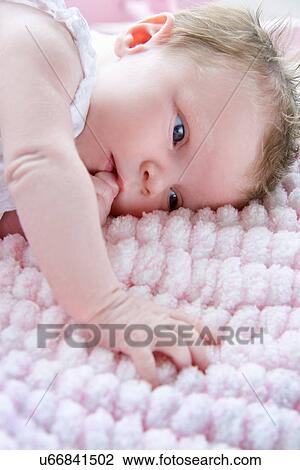 Baby girl lying on side sucking finger View Large Photo Image Stock Image - Baby girl lying on side sucking finger. Fotosearch