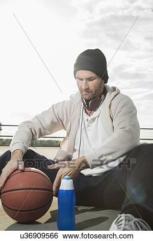 Stock Photograph - Basketball player on floor with basketball. Fotosearch