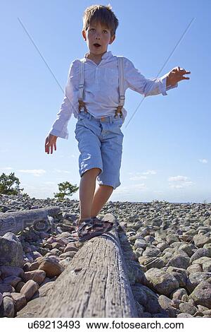 Boy balancing on log on beach View Large Photo Image Stock Image - Boy balancing on log on beach. Fotosearch