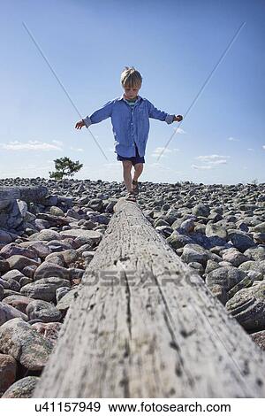Boy balancing on log on beach View Large Photo Image Stock Photo - Boy balancing on log on beach. Fotosearch