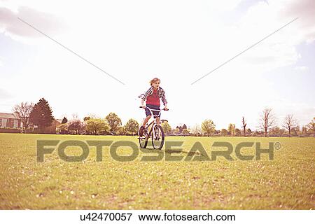 Stock Photo - Boy cycling on playing field. Fotosearch