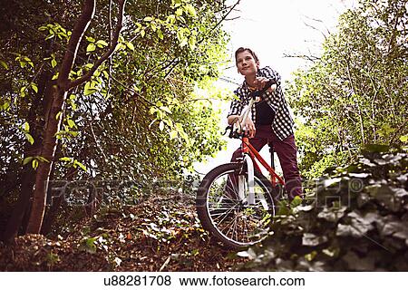 Boy cycling through forest View Large Photo Image Stock Photo - Boy cycling through forest. Fotosearch