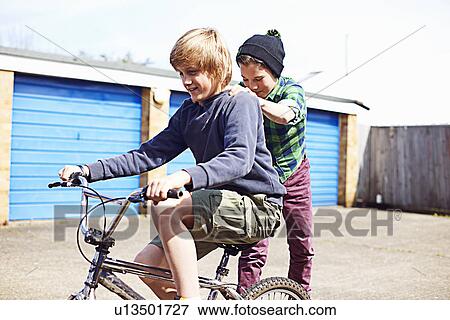 Stock Photo - Boy giving friend a ride on back of bike. Fotosearch