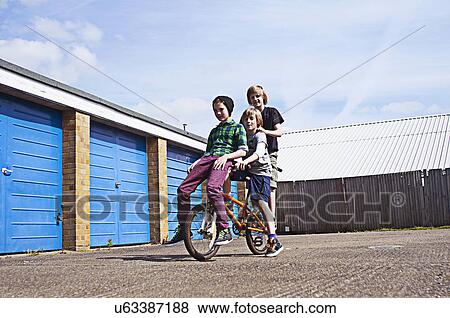 Stock Photo - Boy giving friends a ride on bike. Fotosearch