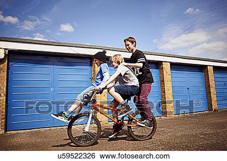 Boy giving two friends a ride on bike View Large Photo Image Stock Photograph - Boy giving two friends a ride on bike. Fotosearch