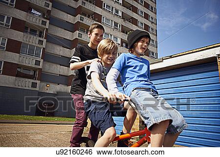 Stock Photograph - Boy giving two friends a ride on bike. Fotosearch