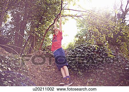 Stock Image - Boy hanging from tree. Fotosearch