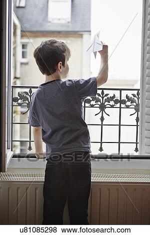 Boy launching paper plane from window View Large Photo Image Stock Photo - Boy launching paper plane from window. Fotosearch