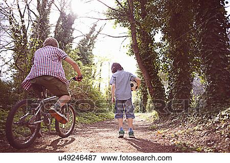 Boy on bike with friend on forest path View Large Photo Image Stock Photo - Boy on bike with friend on forest path. Fotosearch