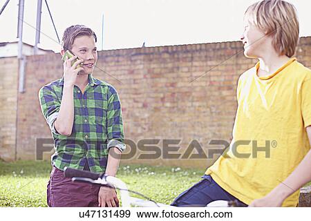 Stock Photo - Boy using cell phone with friend. Fotosearch