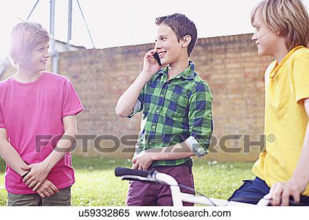 Stock Photography - Boy using cell phone with two friends. Fotosearch