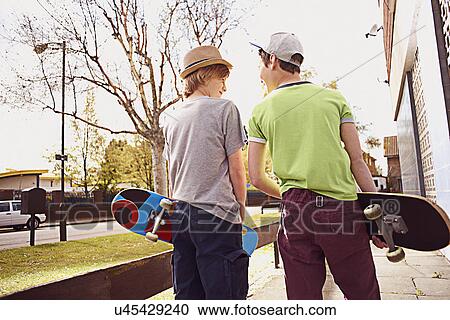 Stock Image - Boys carrying skateboards. Fotosearch