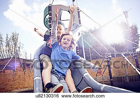 Stock Photograph - Boys coming down slide. Fotosearch