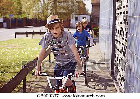 Boys cycling on pavement View Large Photo Image Stock Photo - Boys cycling on pavement. Fotosearch