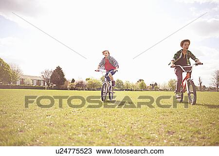 Stock Image - Boys cycling on playing field. Fotosearch