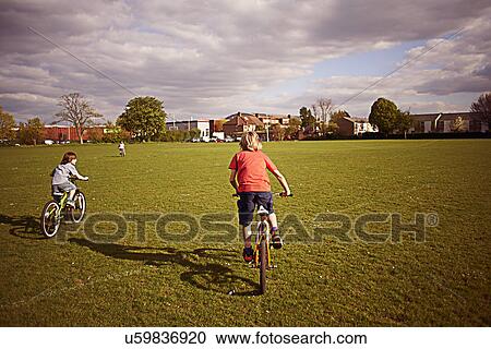 Stock Image - Boys cycling on playing field. Fotosearch