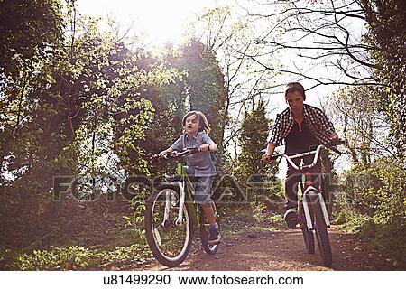 Stock Image - Boys cycling through forest. Fotosearch