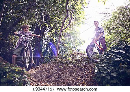 Stock Photo - Boys cycling through forest. Fotosearch