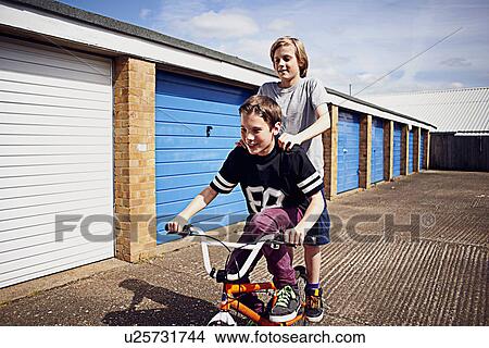 Picture - Boys giving friend a ride on bike. Fotosearch