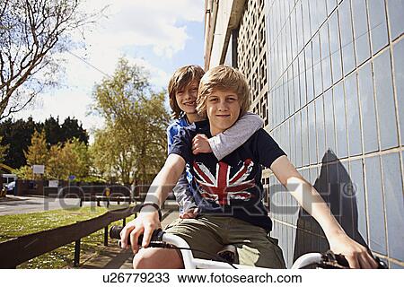 Boys giving friend a ride on bike View Large Photo Image Stock Image - Boys giving friend a ride on bike. Fotosearch