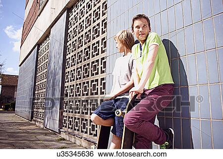 Boys leaning against wall with skateboards View Large Photo Image Stock Photograph - Boys leaning against wall with skateboards. Fotosearch